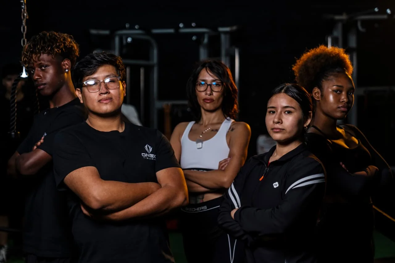 Grupo de socios de ONEX Club posando juntos en la sala de entrenamiento